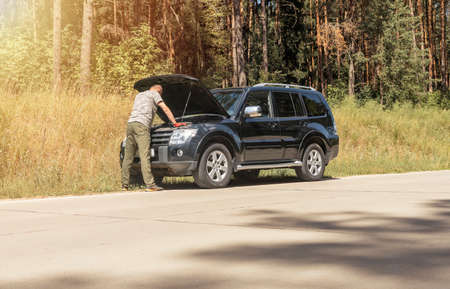 Man driver standing near car with hood raised up and checking for problems.の写真素材