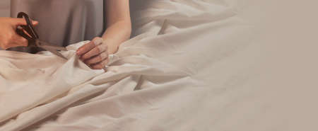 Sewing background with seamstress hands cutting natural fabric with scissors and copy space for...