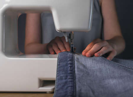 Working with denim textile on sewing machine. Fashion design.