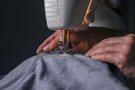 Man working with denim material on sewing machine close up. Fashion design.の写真素材