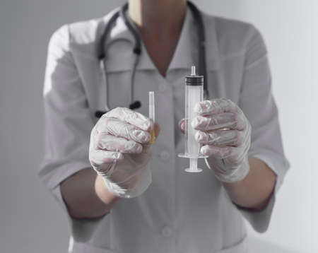 Syringe and needle in doctors or nurse hands, giving it toward.