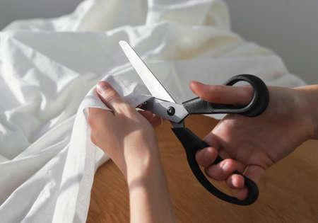 Seamstress hands cutting cotton cloth with sewing scissors. Dressmaker closeup.