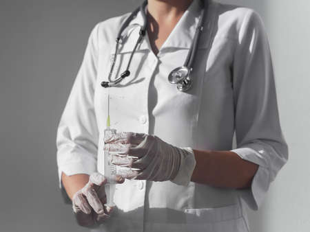 Syringe with sharp needle in doctors or nurse hands in gloves.の写真素材
