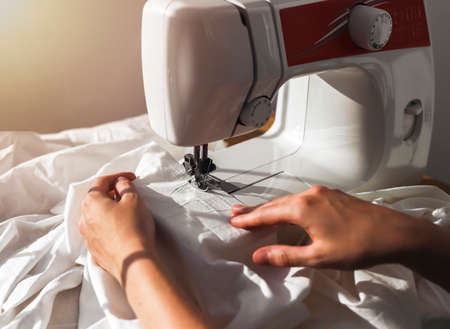 Women hands with natural cotton cloth. Work process at sewing machine, Working with textile.の写真素材