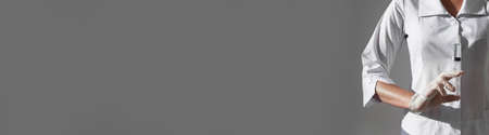 Syringe with needle in doctors hands on gray long wide banner with copy space for text for web sites.の写真素材