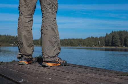Fishermans legs on wood pier while fishing in summerの写真素材