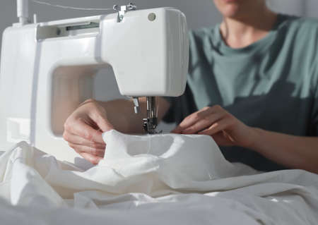 Cotton cloth at sewing machine with seamstress at work process, closeup.の写真素材