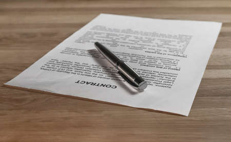 Legal paper contract and pen on wood desk. Agreement.の写真素材