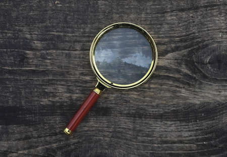 Magnifying glass on wood aged weathered background. Magnification concept.の写真素材