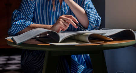Open books, textbooks close up. Education concept. Women hand with pen taking notes, reading, preparing for exam.の写真素材