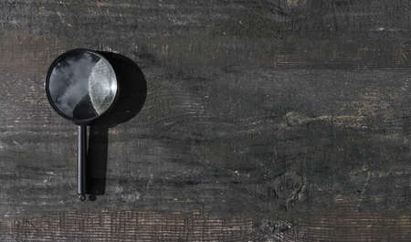 Magnifying glass on wood aged background with copy space for text. Wooden banner with copyspace.の写真素材