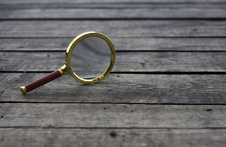 Magnifying glass on wooden plank background with copyspace.