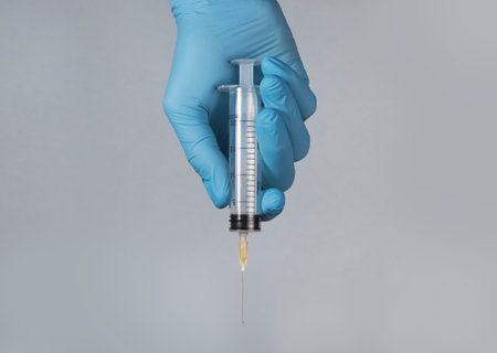 Syringe with needle in doctors hands in glove.の写真素材