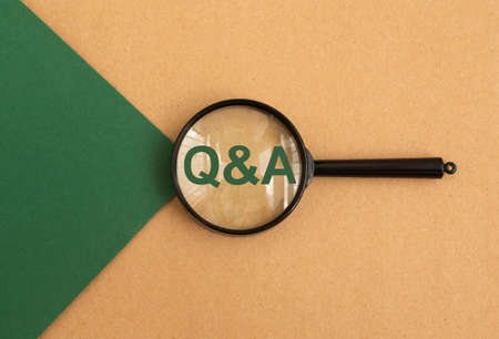 QnA acronym through magnifying glass on green and brown paper, top view. Concept of eco questions and answers.の写真素材