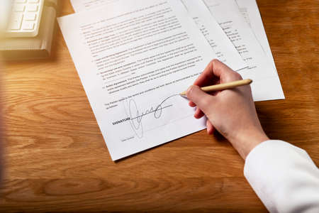 Contract signature concept. Female hand putting her sign on legal business agreement with pen.
