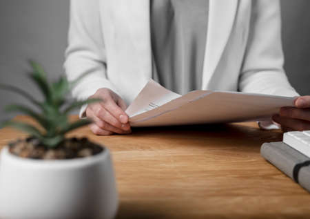 Reading and studying business contract concept. Woman with legal agreement in hands over office desk.の写真素材