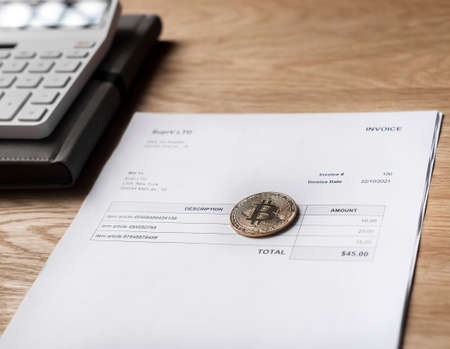 Bitcoin coin on paper invoice. Paying with crypto currency concept.
