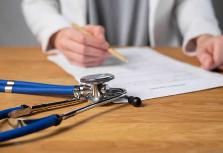 DOCTOR SIGNING MEDICAL INSURANCE CONTRACT. Health care documents, policy concept.