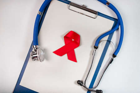 Red ribbon bow and stethoscope. HIV and AIDS check and awareness concept.