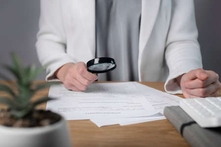 Magnifying glass studying paper document, legal business contract, agreement on office desk.の写真素材