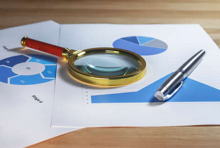 Magnifying lens on documents with business charts and graphs.