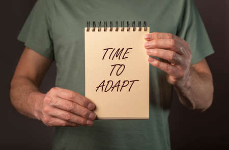 Time to adapt word. New normal concept. Text in male hands.
