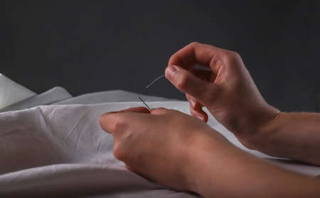 Manual sewing with needle, thread and natural textile.の写真素材
