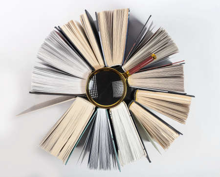 Magnifier among books around. Concept of knowledge, research and studying. Magnifying glass in textbook circle.の写真素材