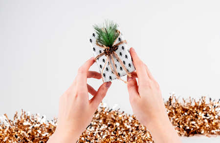 Eco gift box in hands and Christmas glitter on white background.