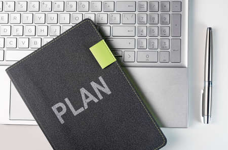 Plan word on business planner notebook on laptop keyboard and pen of silver color, top view.の写真素材