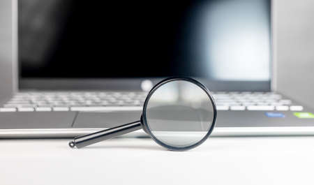 Laptop through magnifying lens. Internet search and SEO research concept.