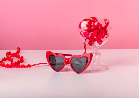 Valentines day concept. Hearts ribbon and red shaped glasses on pink background.の写真素材