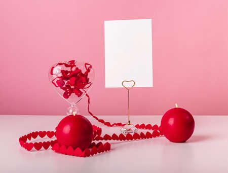 Valentines day postcard. Hearts ribbon and candles at table on pink background. Still life in love and romantic style. Mockup. High quality photoの写真素材