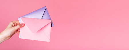 Banner with hand holding envelopes on pink background. Copy space.の写真素材