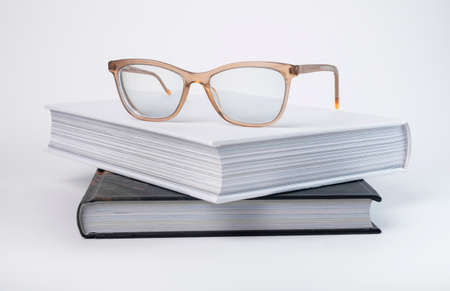 Books stack with eyeglasses. Encyclopedia, bible, code or novel on grey background. Reading and getting knowledge concept. High quality photoの写真素材