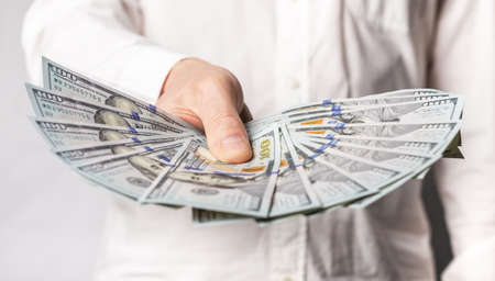 Businessman hand closeup showing one hundred dollar bills. Business income concept. High quality...