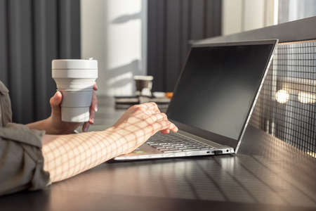 Woman hands closeup holding takeaway eco cup and using laptop for work, education, social...