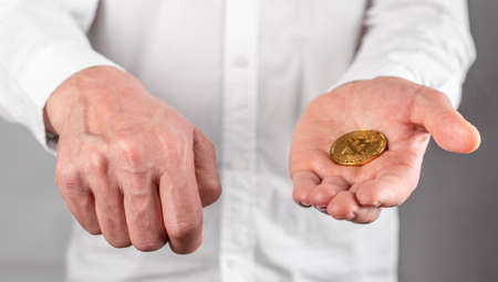 Businessman hand closeup holding bitcoin. Focus with coin. Manipulation, trading and transaction with cryptocurrency concept. High quality photoの写真素材