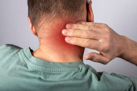 Man suffering from neck pain. Head back with red point closeup. Health problems and medicine concept. High quality photoの写真素材
