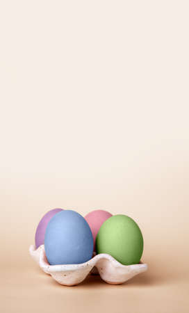 Banner with multicolored Easter eggs in carton box on beige background. Symbol of religious holiday. Copy space. High quality photoの写真素材