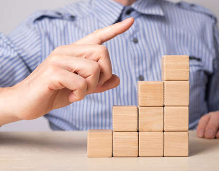 Man hand pointing to career ladder top, pinnacle. Stairs from wooden blocks. Professional...
