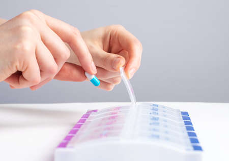 Woman hand taking pill, vitamin from case, organizer. Sorting tablets for daily medication. Health care and diseases cure. High quality photoの写真素材