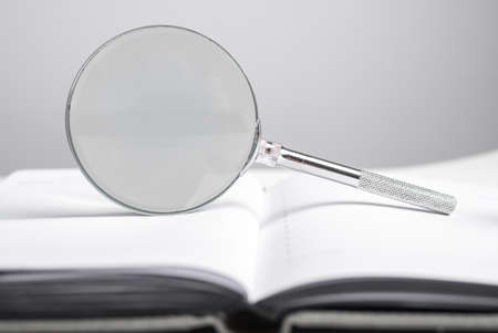Magnifying glass at notebook, organizer. Schedule, agenda analysis, time management concept. High...
