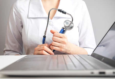 Doctor with stethoscope sitting at desk with laptop and giving consultation to patient. Healthcare...