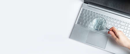 Banner with woman hand holding magnifying glass over laptop keyboard. Information search on Internet...