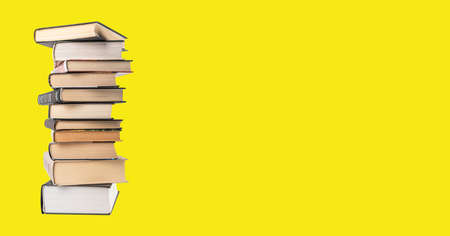 Ad school banner with stack of classics books, literature pile on yellow background with copy space. High quality photoの写真素材