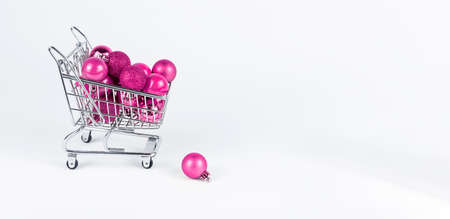 Banner with pink Christmas balls in supermarket trolley. Buying tree ornaments, decoration. Space for text. High quality photoの写真素材
