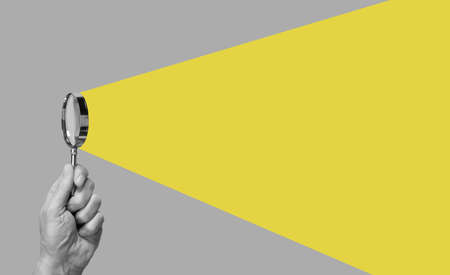 Man hand with magnifying glass. Yellow ray coming from loupe. Conducting check, information search...