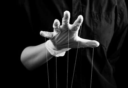 Hand in medical glove with strings on fingers. Deception in medicine and pharmacy, conspiracy theory, health care fraud, control and power over patient concept. Black and white. High quality photoの写真素材