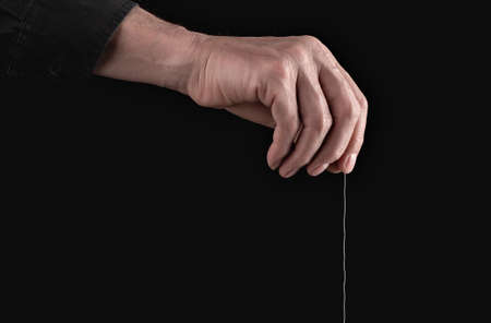 Man hand holding string for manipulation, exploit, control. Abuse and toxic relationship. Manipulator making person feel fearful, guilty. High quality photoの写真素材